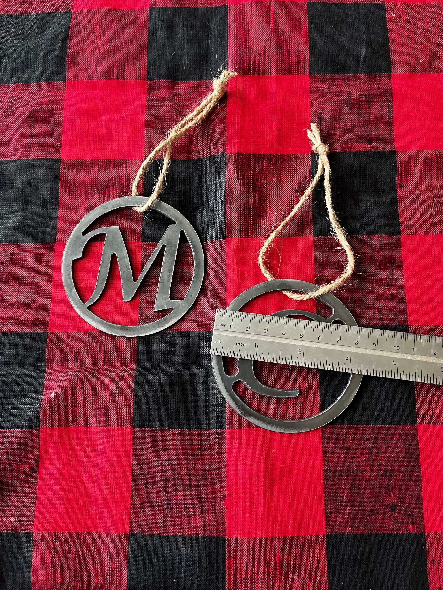 Monogram steel ornament shown with ruler for scale